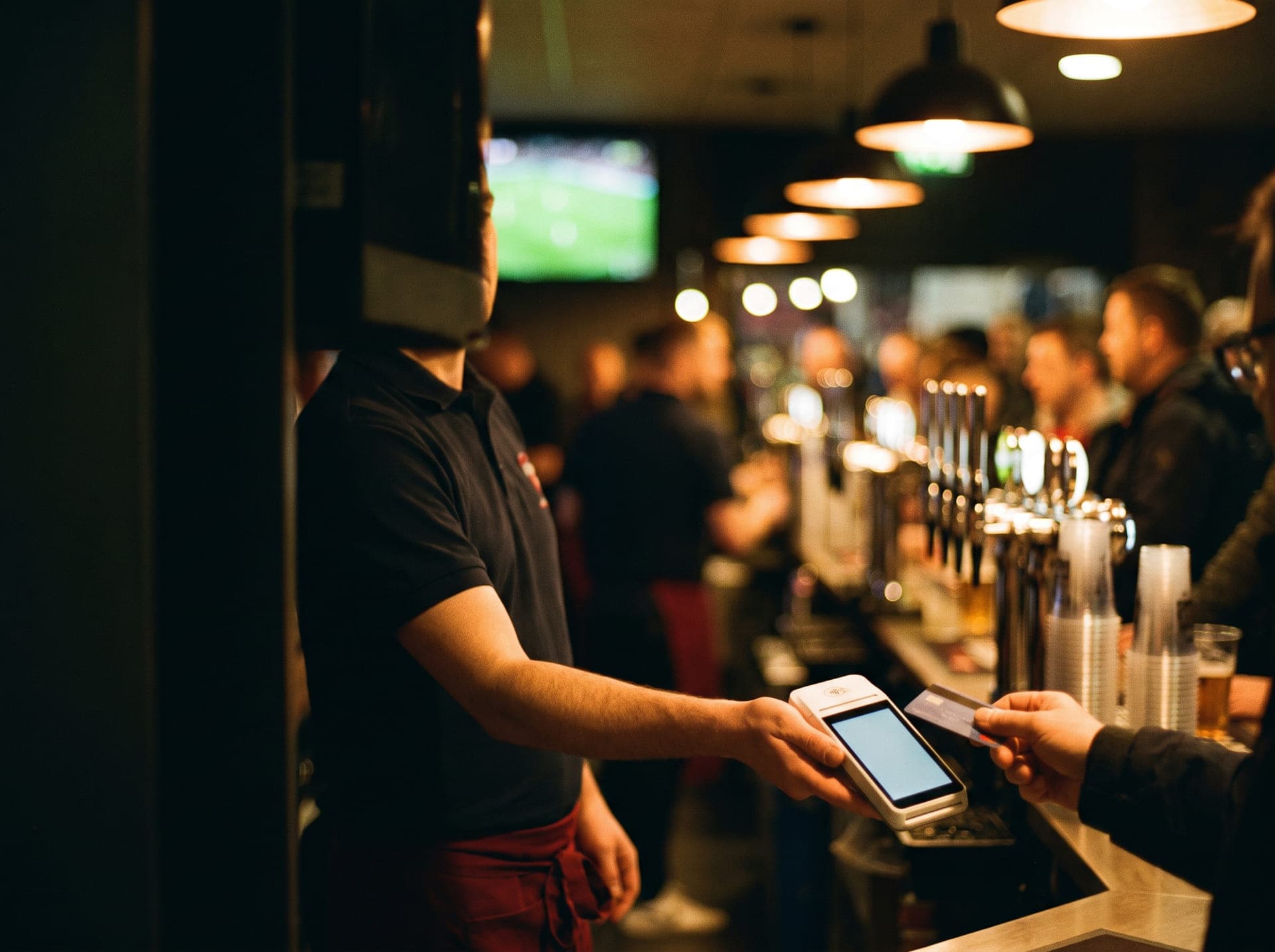 Personale di sala che incassa con il Terminal Qodeup al bar di uno stadio durante una partita